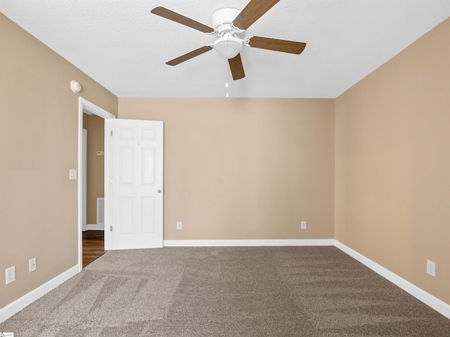 spare room with ceiling fan, dark carpet, and a textured ceiling