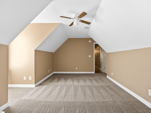 additional living space with ceiling fan, vaulted ceiling, light carpet, and a textured ceiling