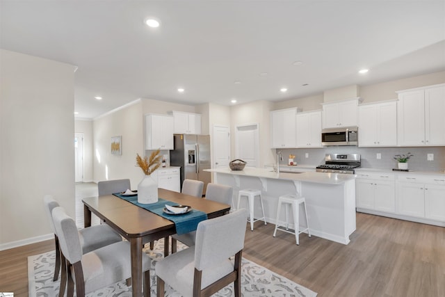 dining space with sink, ornamental molding, and light wood-type flooring