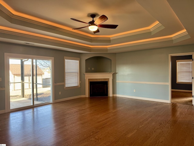 unfurnished living room with ceiling fan, ornamental molding, a tray ceiling, and hardwood / wood-style floors