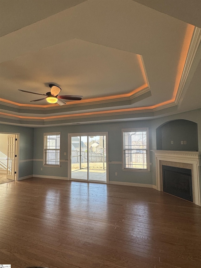 unfurnished living room featuring hardwood / wood-style flooring, ornamental molding, a raised ceiling, and ceiling fan