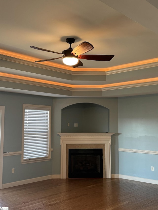 unfurnished living room with hardwood / wood-style flooring, ornamental molding, ceiling fan, and a tray ceiling