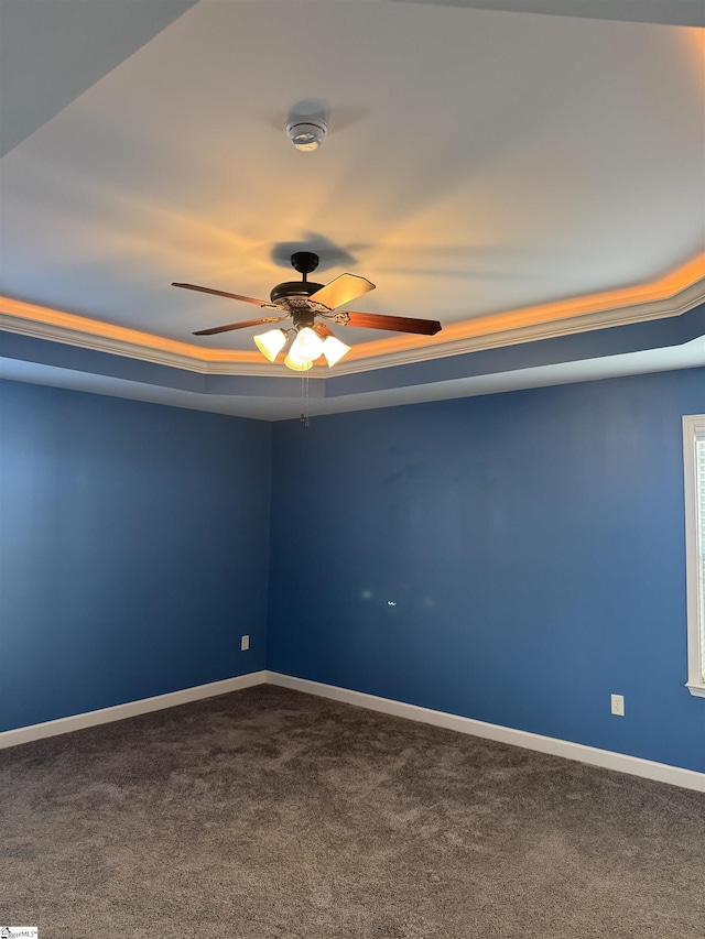 carpeted spare room with ceiling fan and a raised ceiling