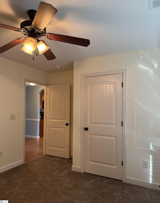 interior space featuring ceiling fan and dark colored carpet