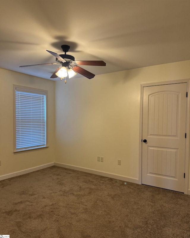 spare room with ceiling fan and dark colored carpet