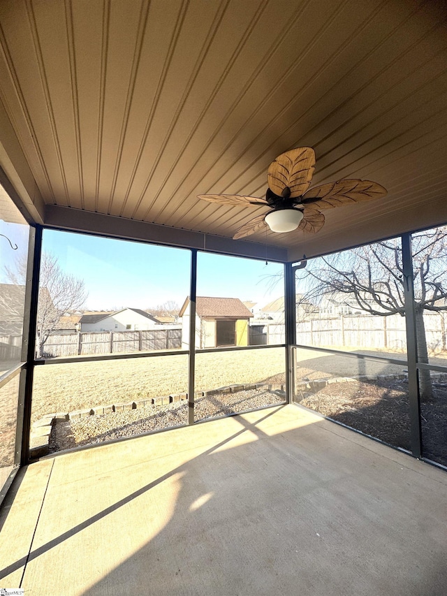 unfurnished sunroom featuring wood ceiling, a wealth of natural light, and ceiling fan