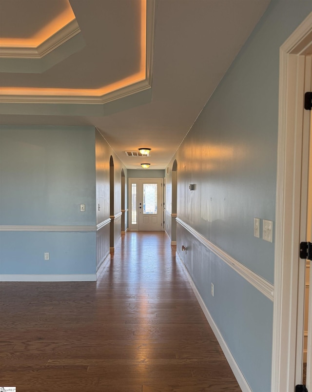 hall featuring crown molding, dark wood-type flooring, and a raised ceiling