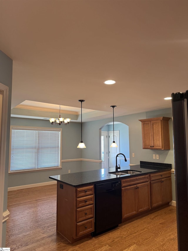 kitchen with decorative light fixtures, black dishwasher, sink, light hardwood / wood-style floors, and a tray ceiling