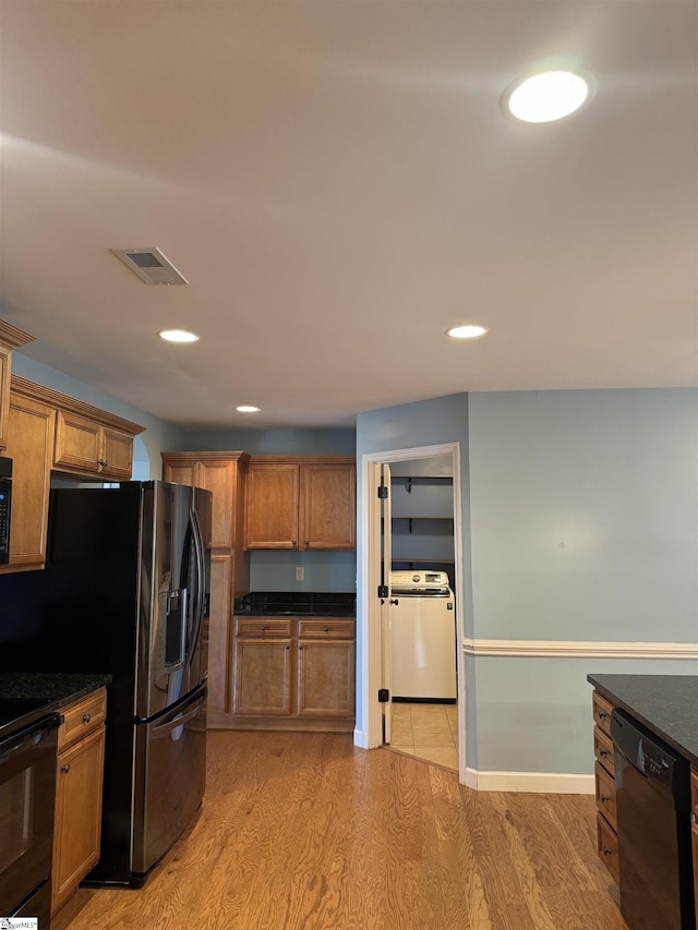 kitchen with washer / clothes dryer, black appliances, and light hardwood / wood-style floors