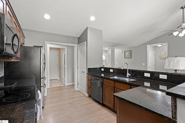 kitchen featuring sink, vaulted ceiling, appliances with stainless steel finishes, dark stone counters, and light hardwood / wood-style floors