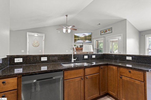 kitchen featuring sink, vaulted ceiling, dark stone countertops, stainless steel dishwasher, and ceiling fan