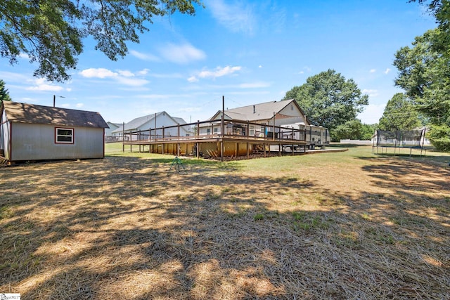 view of yard featuring a trampoline, a shed, and a deck