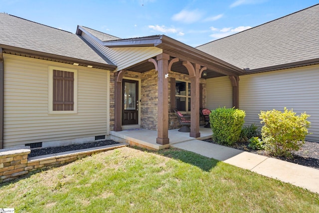 view of exterior entry featuring a porch and a yard