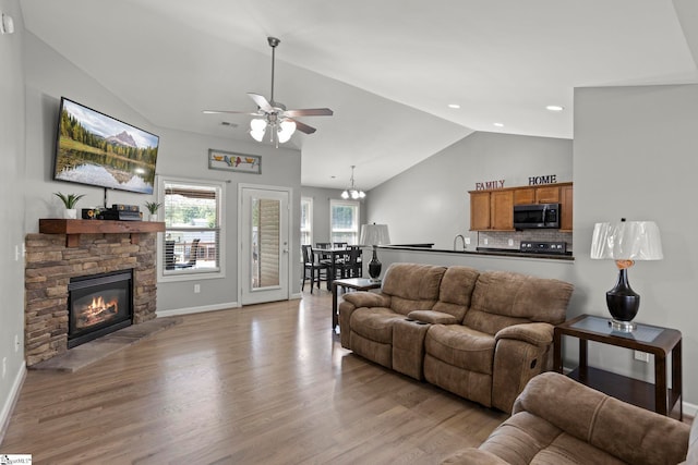 living room with ceiling fan, lofted ceiling, a fireplace, and light wood-type flooring