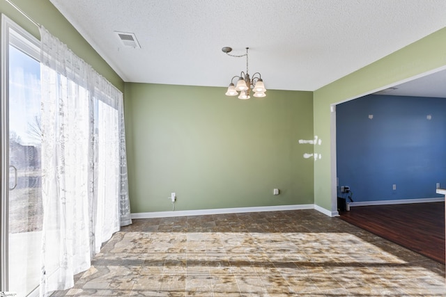 spare room with dark hardwood / wood-style flooring, a textured ceiling, and an inviting chandelier