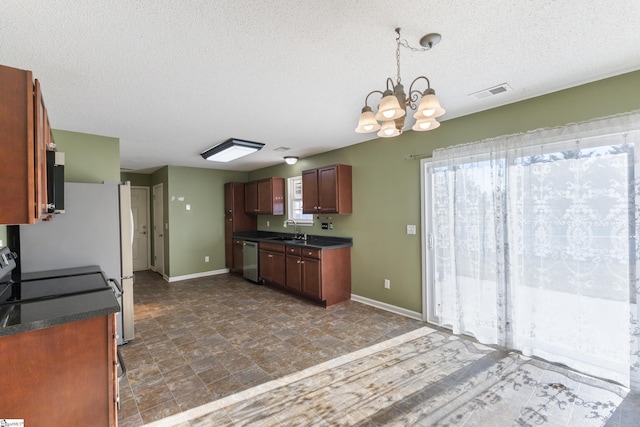 kitchen featuring sink, appliances with stainless steel finishes, an inviting chandelier, hanging light fixtures, and a textured ceiling