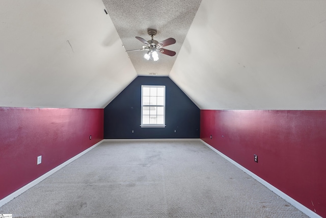 additional living space featuring ceiling fan, light colored carpet, vaulted ceiling, and a textured ceiling