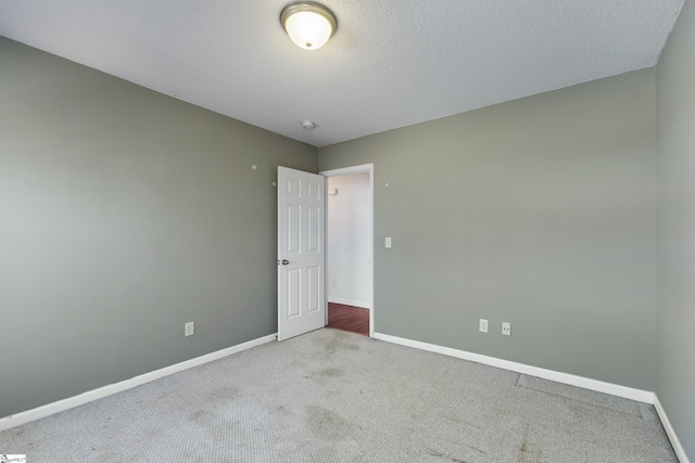 carpeted empty room with a textured ceiling