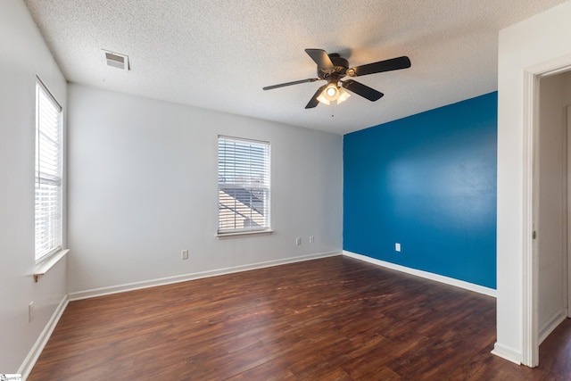 spare room with ceiling fan, plenty of natural light, a textured ceiling, and dark hardwood / wood-style flooring