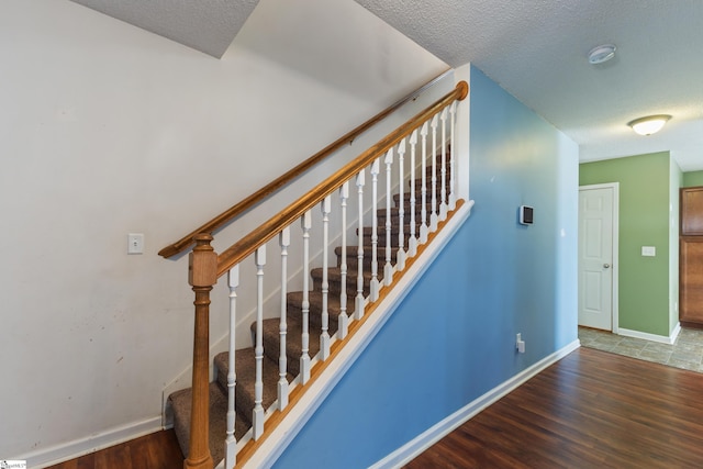 stairway featuring hardwood / wood-style floors and a textured ceiling