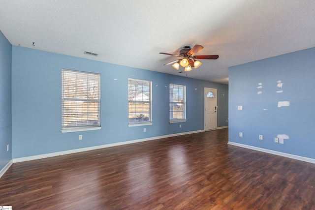 empty room with a textured ceiling, dark wood-type flooring, and ceiling fan