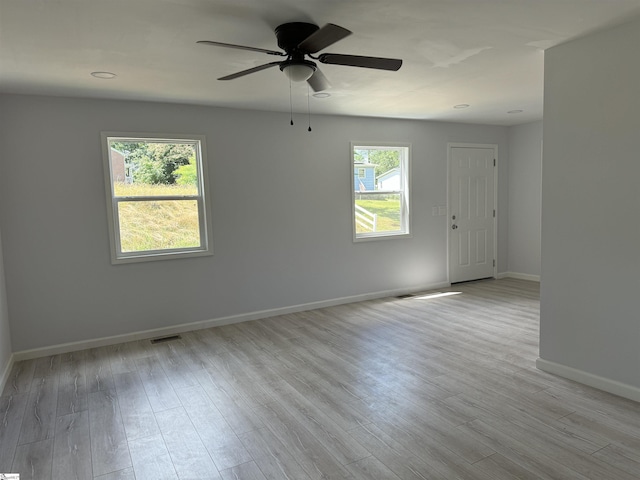 empty room featuring ceiling fan, a healthy amount of sunlight, and light hardwood / wood-style floors