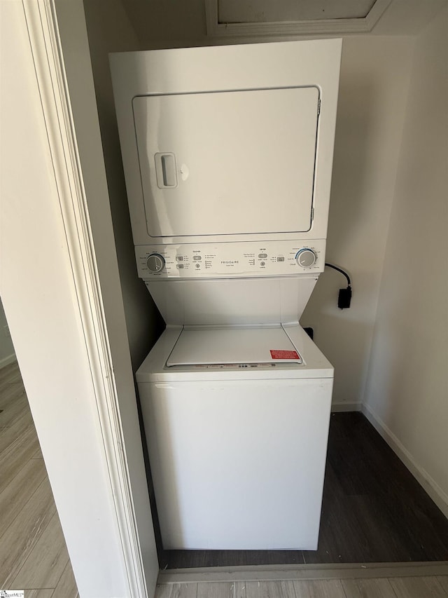 washroom featuring stacked washer and clothes dryer and wood-type flooring