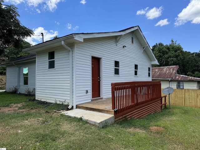 rear view of house with a wooden deck and a yard