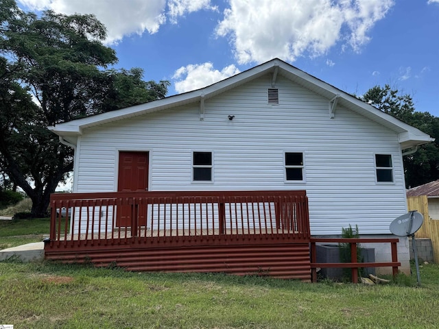 rear view of property with cooling unit, a deck, and a lawn