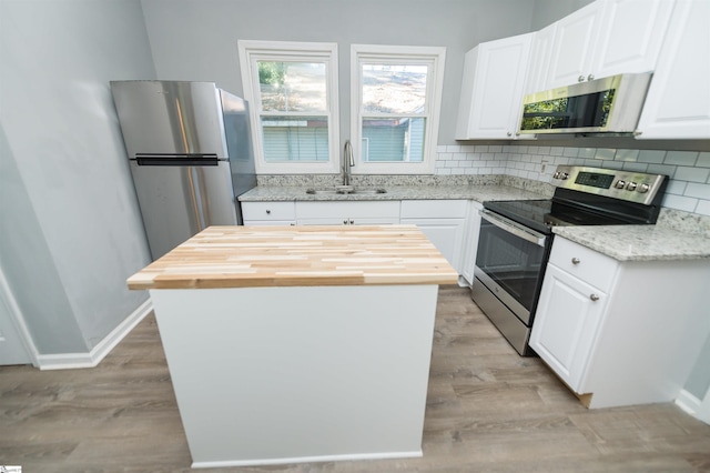 kitchen with stainless steel appliances, a center island, sink, and white cabinets