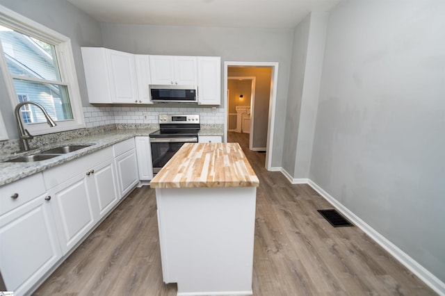 kitchen with white cabinetry, appliances with stainless steel finishes, sink, and wood counters