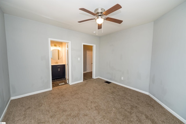 unfurnished bedroom featuring dark colored carpet, ceiling fan, and ensuite bath