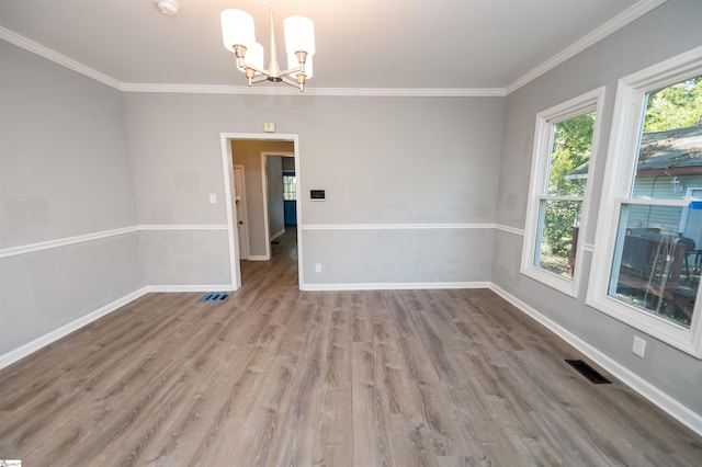 spare room with ornamental molding, wood-type flooring, and a notable chandelier