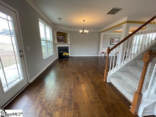 312 Engelmann Ln, Simpsonville, SC 29680 - unfurnished living room featuring crown molding, dark wood-type flooring, and a chandelier