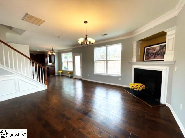 312 Engelmann Ln, Simpsonville, SC 29680 - unfurnished living room with ornamental molding, dark hardwood / wood-style floors, and a chandelier