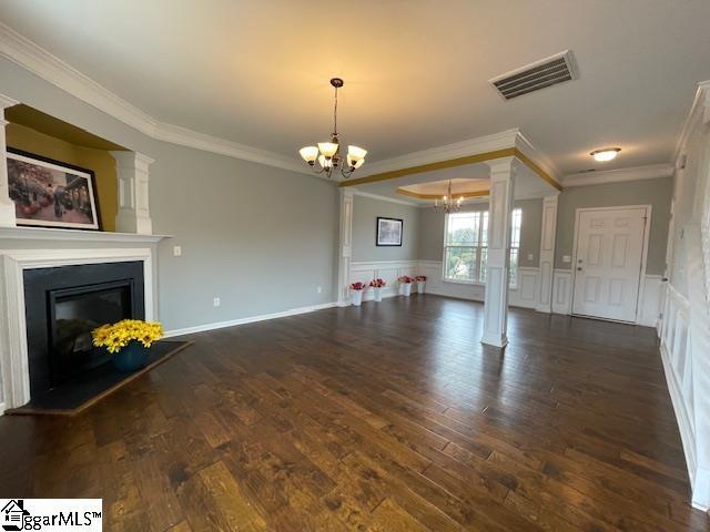 312 Engelmann Ln, Simpsonville, SC 29680 - unfurnished living room featuring an inviting chandelier, ornamental molding, dark hardwood / wood-style flooring, and decorative columns