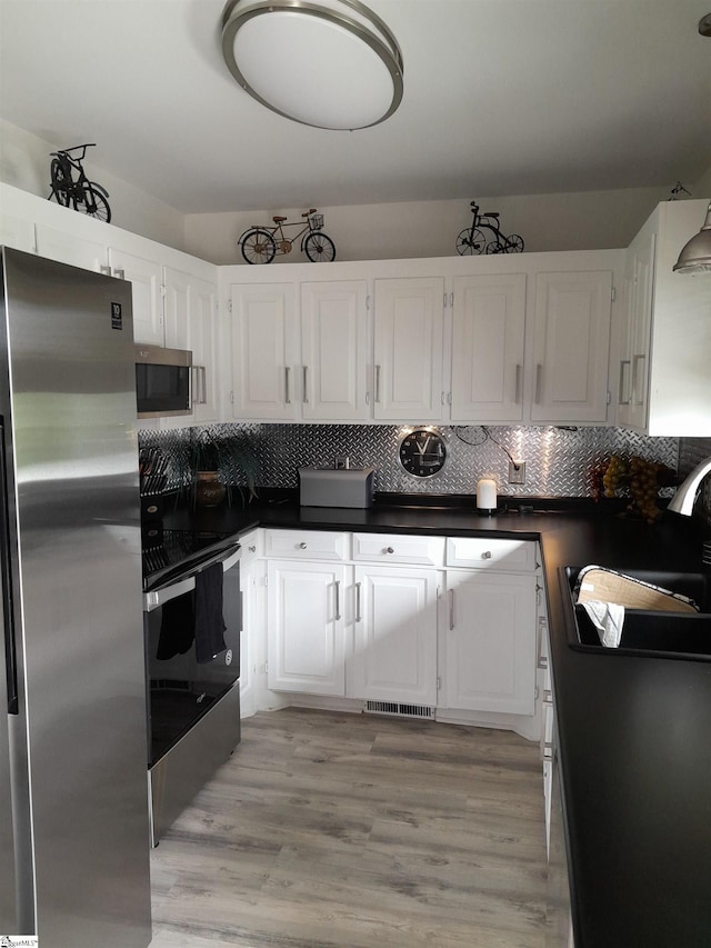 kitchen featuring sink, white cabinets, decorative backsplash, light hardwood / wood-style floors, and stainless steel appliances