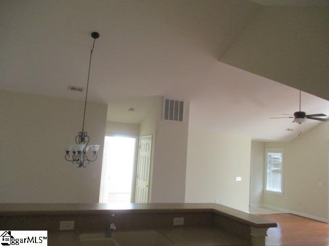 unfurnished room with vaulted ceiling, ceiling fan with notable chandelier, and light wood-type flooring