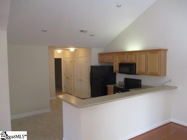 kitchen with kitchen peninsula, high vaulted ceiling, and black appliances