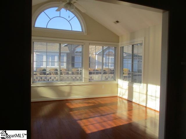 spare room featuring hardwood / wood-style flooring, vaulted ceiling, a wealth of natural light, and ceiling fan