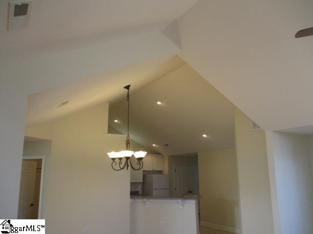 room details featuring white refrigerator and an inviting chandelier