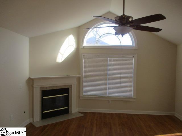 unfurnished living room featuring a tile fireplace, vaulted ceiling, dark hardwood / wood-style floors, and ceiling fan