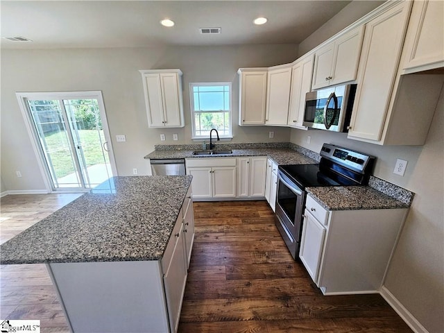 kitchen with a kitchen island, stone countertops, appliances with stainless steel finishes, sink, and white cabinets