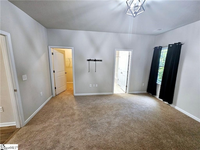 unfurnished bedroom featuring connected bathroom, a spacious closet, and light carpet