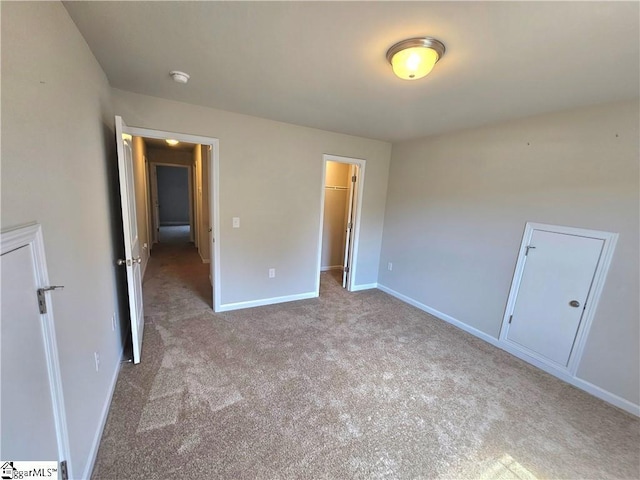 unfurnished bedroom with a spacious closet and light colored carpet