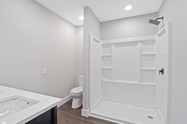 bathroom featuring wood-type flooring, a shower, vanity, and toilet