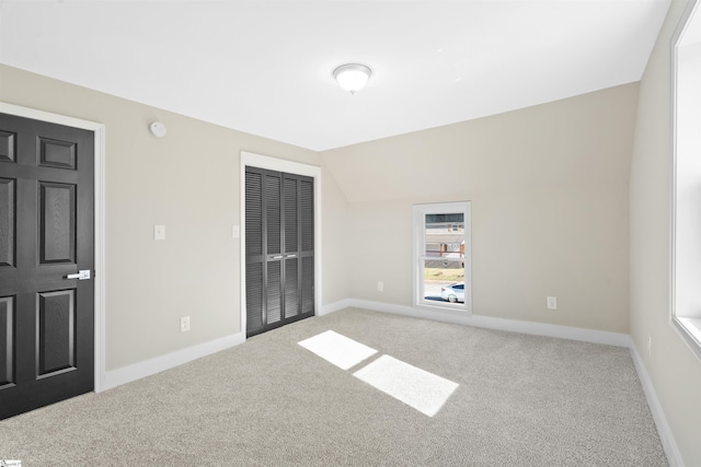 unfurnished bedroom with lofted ceiling, carpet floors, and a closet