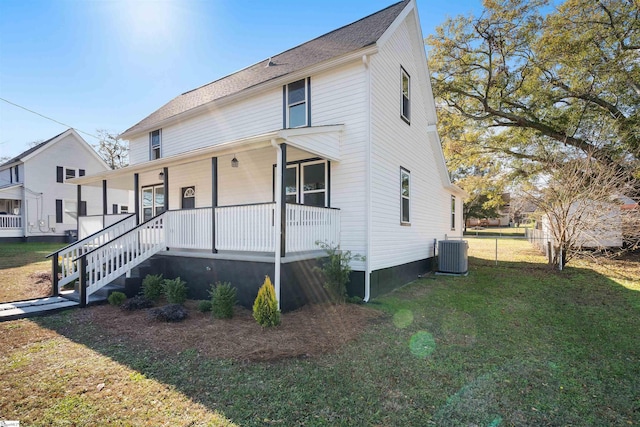 view of front facade featuring central AC, covered porch, and a front yard