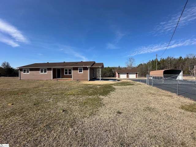 back of property with a garage, a carport, a yard, and an outbuilding