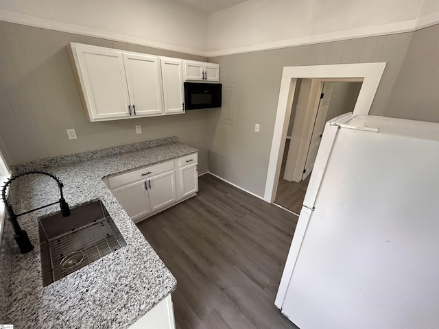 kitchen featuring white refrigerator, white cabinetry, dark hardwood / wood-style floors, and light stone counters